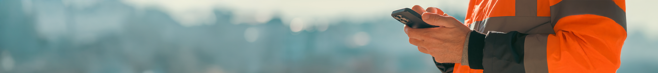 construction worker holding a mobile in an orange jacket